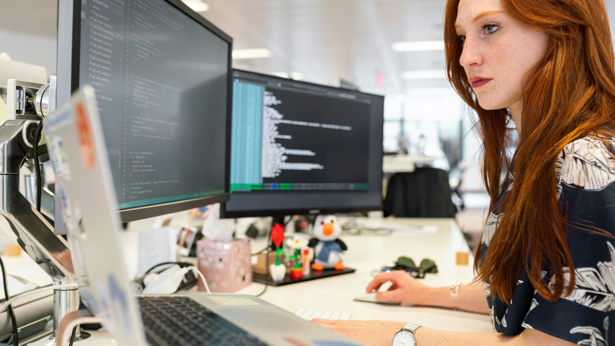 A woman at a desk with multiple computers representing a professional working at Revpanda, an iGaming agency, managing various digital operations to support client growth, including strategies for fast withdrawal casinos.