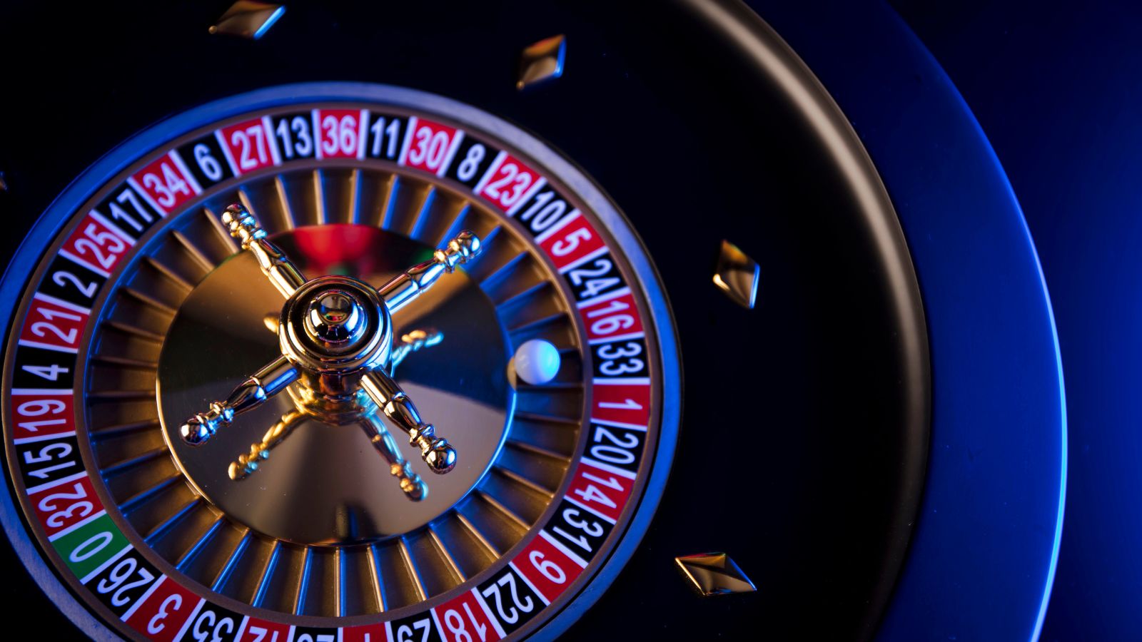 Man playing slotgameson NV Casino website using a laptop, surroundedbycasino chips and coins, representing modern online gambling and bonuses.